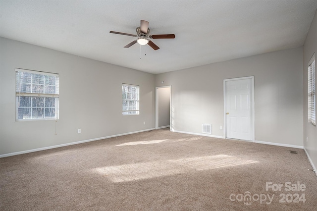 carpeted empty room featuring ceiling fan and a textured ceiling