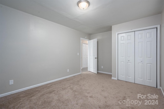 unfurnished bedroom featuring light carpet and a closet