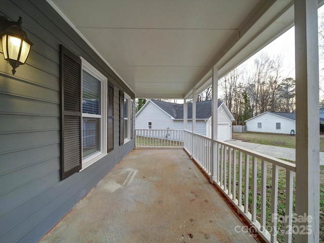 view of patio featuring an outdoor structure, a porch, and a garage