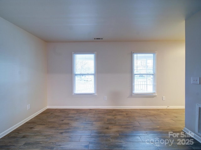 unfurnished room featuring dark wood-type flooring and a wealth of natural light