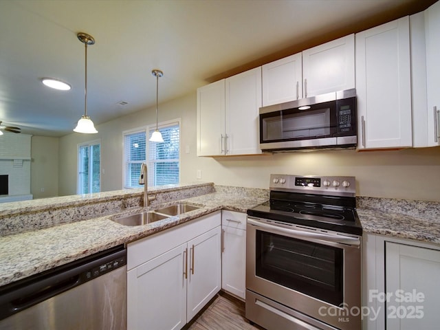 kitchen with white cabinets, stainless steel appliances, sink, hanging light fixtures, and ceiling fan