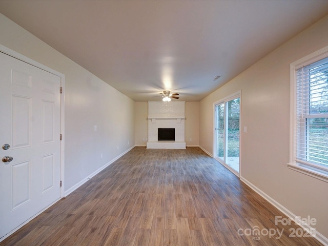 unfurnished living room with a brick fireplace, hardwood / wood-style floors, and ceiling fan