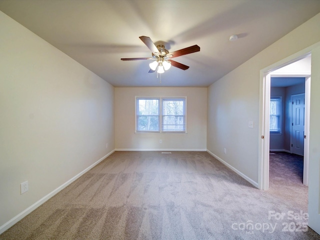 empty room with ceiling fan, light colored carpet, and plenty of natural light