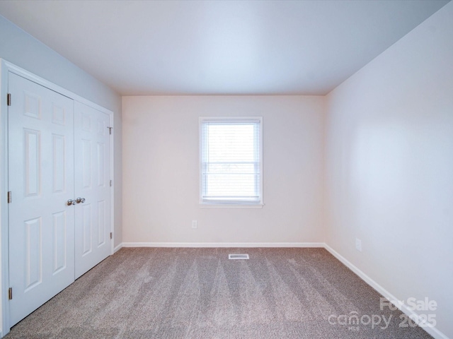 unfurnished bedroom with light colored carpet and a closet