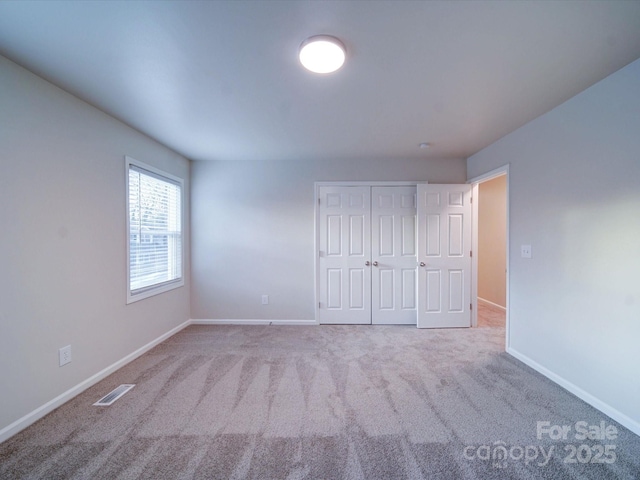 unfurnished bedroom featuring light carpet and a closet