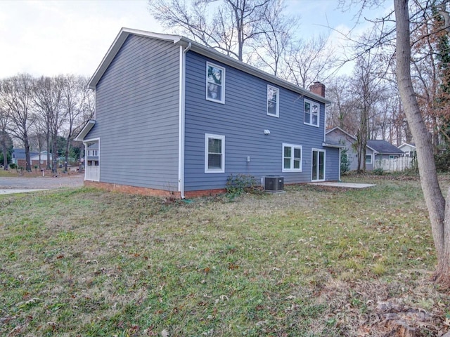 back of property with a lawn and central AC