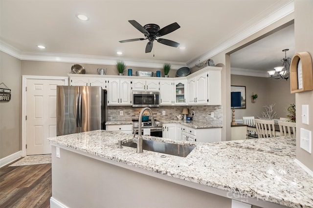 kitchen with appliances with stainless steel finishes, tasteful backsplash, ceiling fan with notable chandelier, sink, and white cabinets