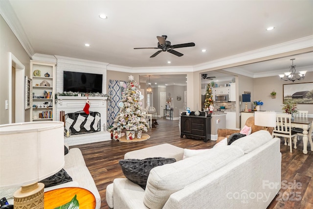 living room featuring a fireplace, ceiling fan with notable chandelier, dark hardwood / wood-style floors, and ornamental molding