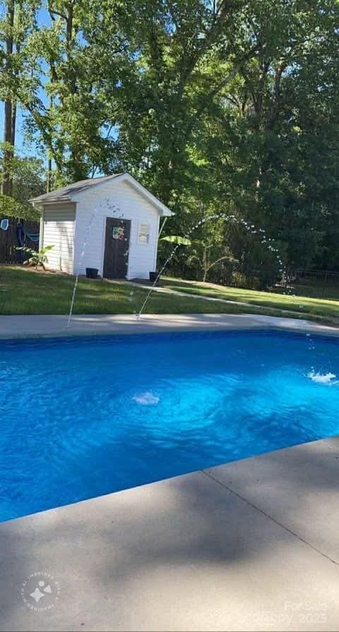 view of pool with a yard and an outbuilding