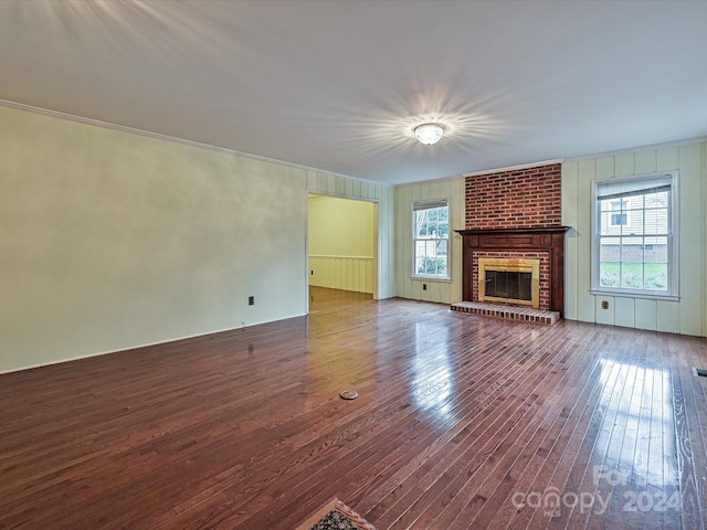 unfurnished living room with wood-type flooring and a brick fireplace