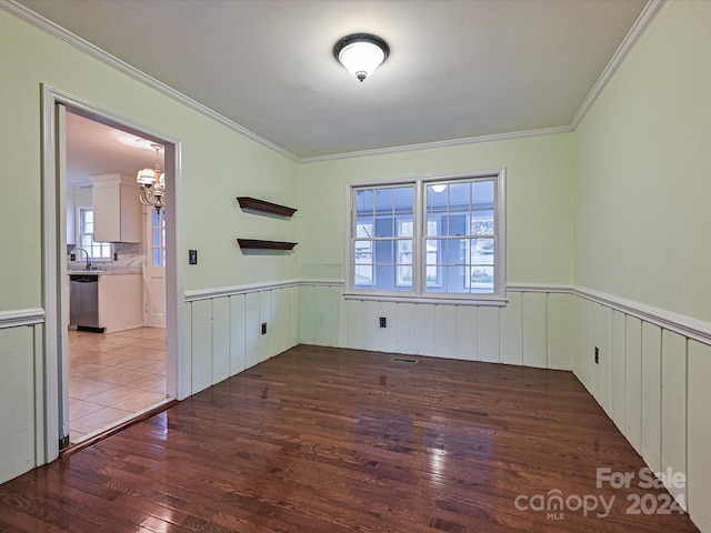 empty room featuring dark hardwood / wood-style flooring, ornamental molding, sink, and an inviting chandelier