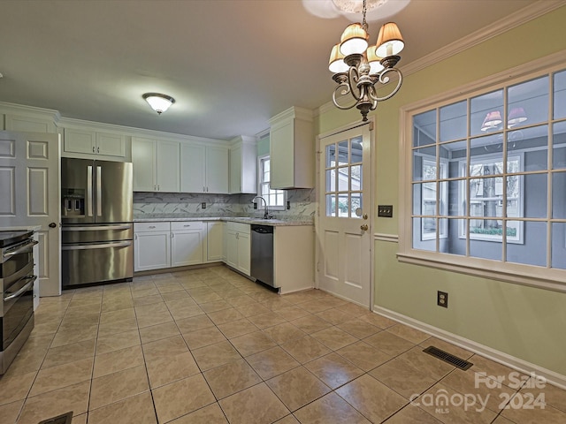 kitchen featuring white cabinetry, a notable chandelier, pendant lighting, decorative backsplash, and appliances with stainless steel finishes