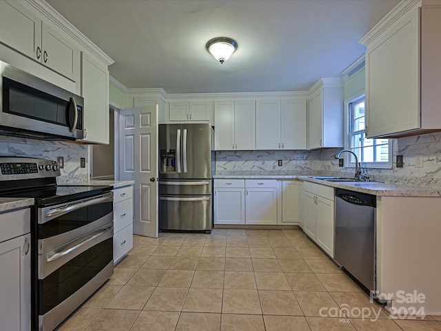 kitchen with decorative backsplash, stainless steel appliances, sink, white cabinetry, and light tile patterned flooring