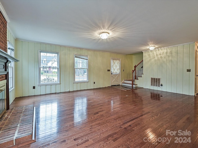 unfurnished living room with wooden walls, a fireplace, and dark hardwood / wood-style floors