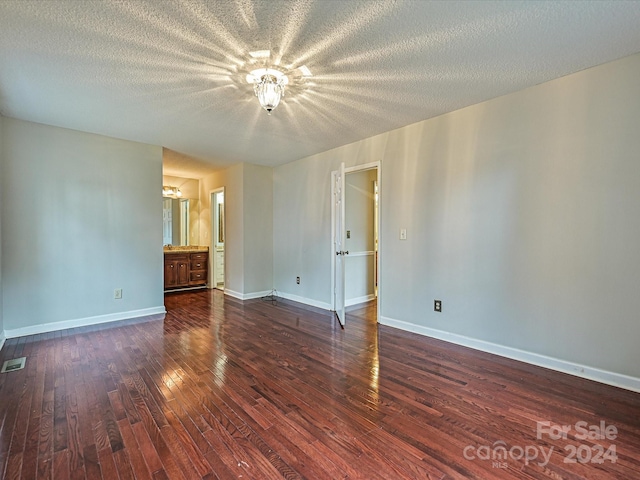 spare room with dark hardwood / wood-style flooring and a textured ceiling