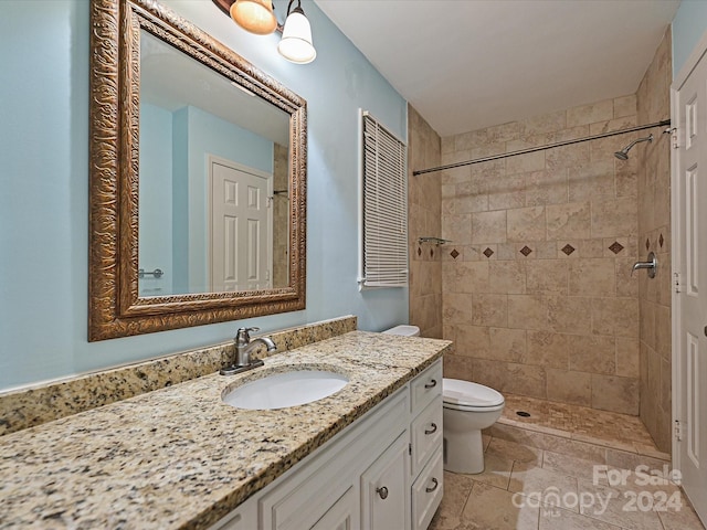 bathroom with a tile shower, vanity, and toilet