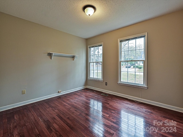 unfurnished room featuring dark hardwood / wood-style floors and a textured ceiling