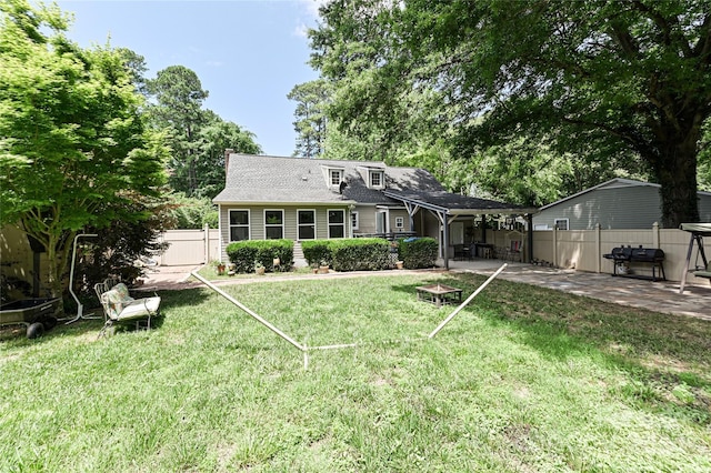 rear view of house with a yard, a patio, and an outdoor fire pit