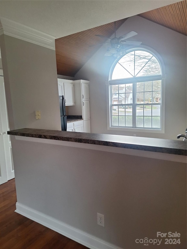 kitchen featuring dark wood-type flooring, vaulted ceiling, white cabinetry, kitchen peninsula, and stainless steel refrigerator