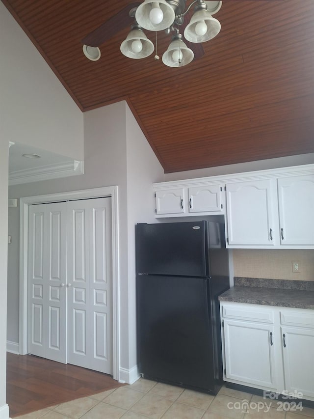 kitchen featuring black refrigerator, white cabinets, vaulted ceiling, and light wood-type flooring