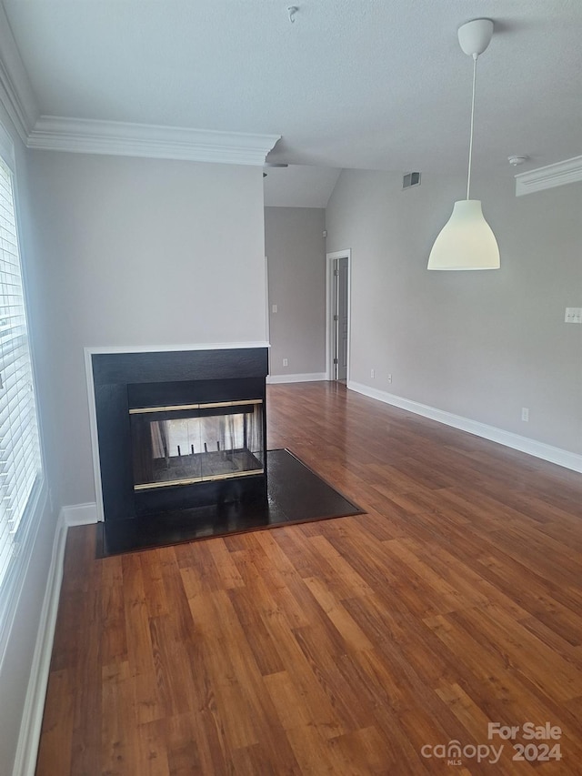 unfurnished room with a multi sided fireplace, crown molding, a wealth of natural light, and dark wood-type flooring