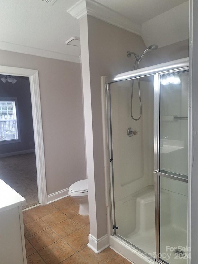 bathroom featuring vanity, tile patterned floors, crown molding, toilet, and a shower with shower door