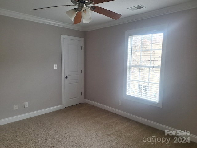 carpeted spare room featuring crown molding and ceiling fan