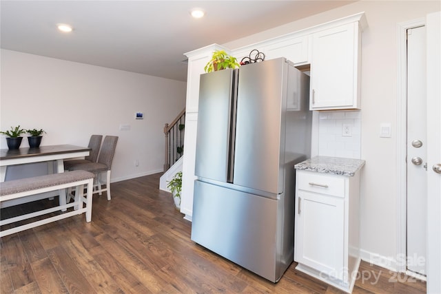 kitchen with white cabinetry, light stone countertops, dark hardwood / wood-style floors, backsplash, and stainless steel fridge