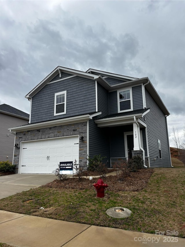 view of front of property featuring an attached garage, stone siding, driveway, and a front yard