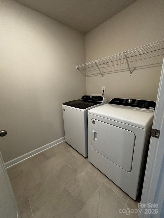 clothes washing area featuring laundry area, washing machine and dryer, and baseboards