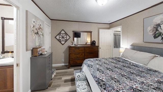 bedroom featuring a textured ceiling, light hardwood / wood-style flooring, ornamental molding, and sink