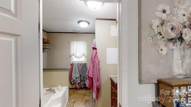 bathroom with vanity, a bathtub, ornamental molding, and a textured ceiling