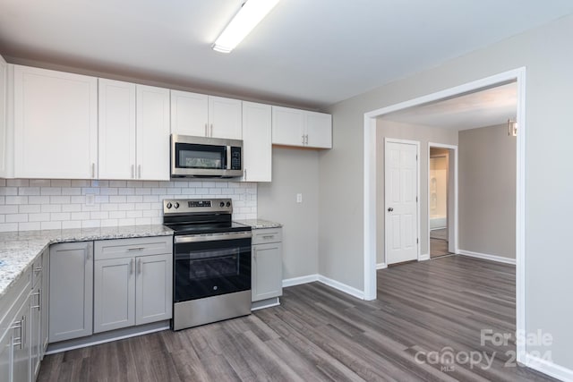 kitchen with decorative backsplash, light stone counters, stainless steel appliances, white cabinets, and dark hardwood / wood-style floors