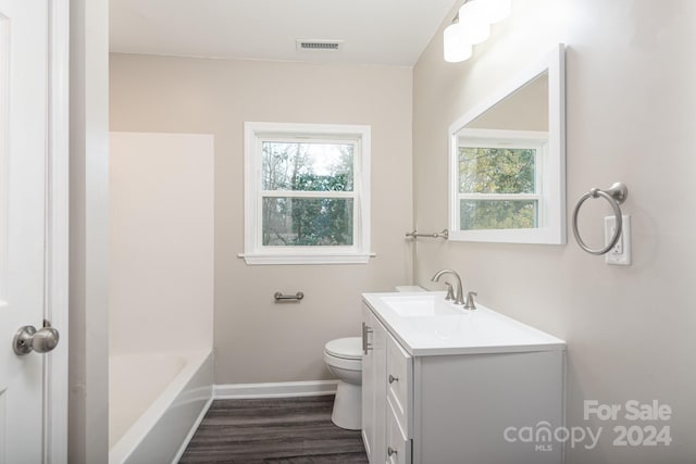 bathroom featuring wood-type flooring, vanity, toilet, and a healthy amount of sunlight