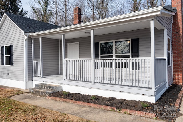 exterior space with covered porch, a shingled roof, and a chimney