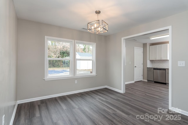 empty room with dark wood-style floors, baseboards, and an inviting chandelier