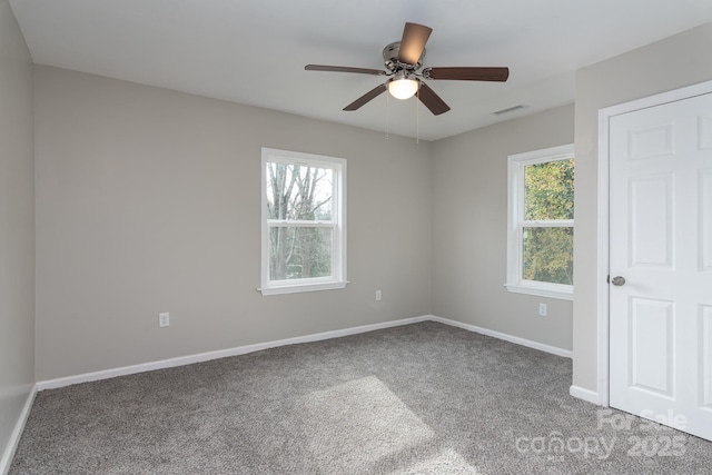 carpeted empty room with baseboards, visible vents, ceiling fan, and a wealth of natural light