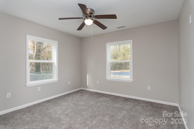 carpeted empty room featuring baseboards, visible vents, and a ceiling fan