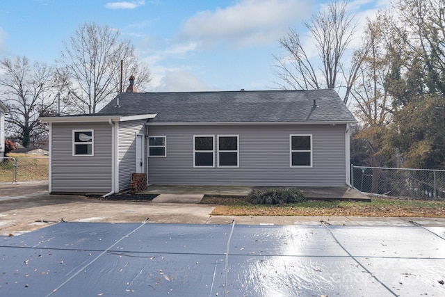 back of house featuring a patio, a shingled roof, fence, and a fenced in pool