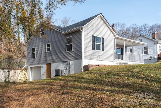 view of front of property featuring a garage, covered porch, central AC, and a front yard