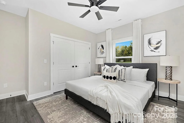 bedroom featuring dark wood-style flooring, a ceiling fan, visible vents, baseboards, and a closet