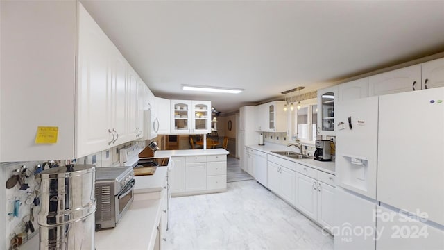 kitchen with sink, white cabinets, hanging light fixtures, and white appliances