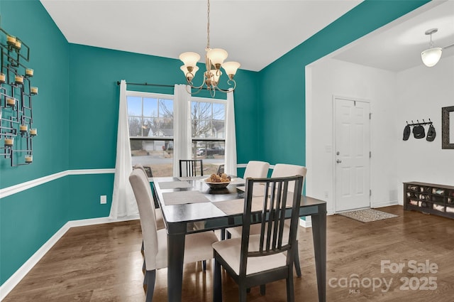 dining space featuring dark wood-type flooring and a chandelier