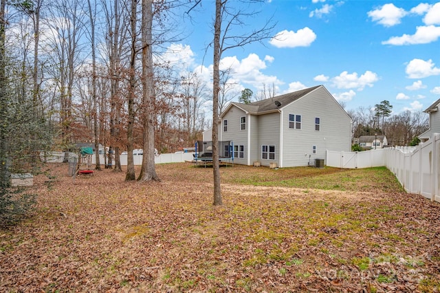 rear view of property with a trampoline and a lawn