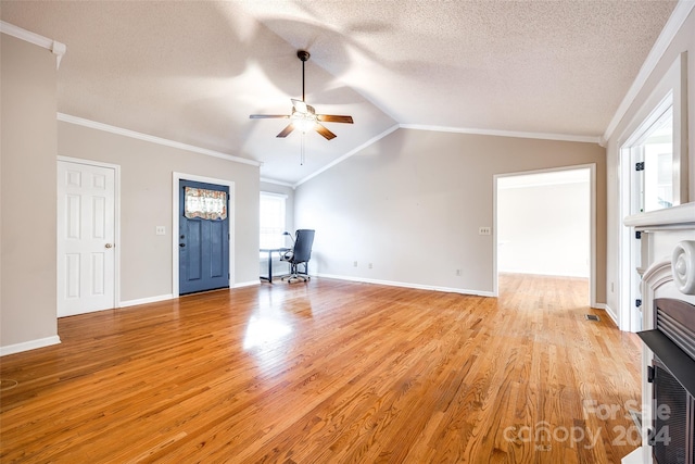 unfurnished living room featuring a textured ceiling, light hardwood / wood-style floors, crown molding, and vaulted ceiling