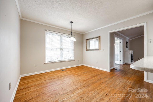 unfurnished dining area featuring crown molding, wood-type flooring, a textured ceiling, and an inviting chandelier