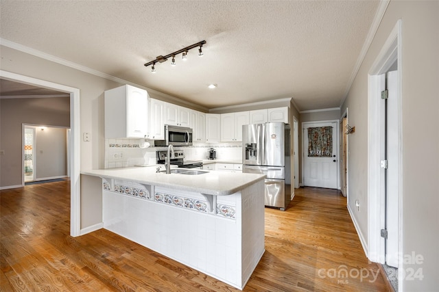 kitchen with sink, kitchen peninsula, a textured ceiling, white cabinets, and appliances with stainless steel finishes