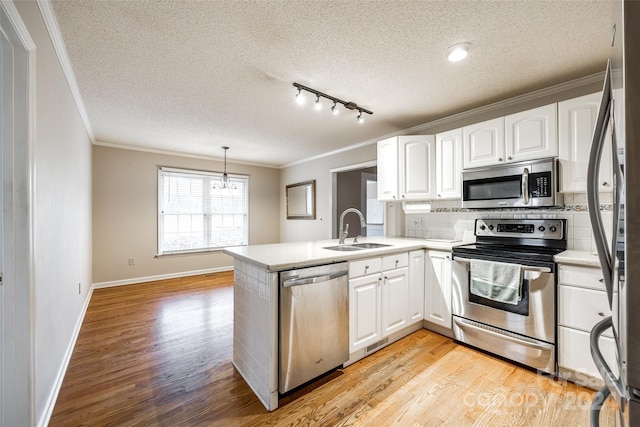 kitchen featuring white cabinetry, sink, stainless steel appliances, kitchen peninsula, and decorative light fixtures