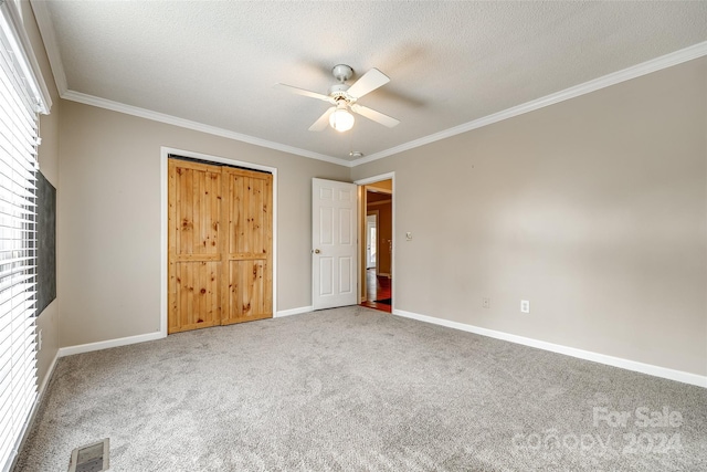 unfurnished bedroom with carpet, ceiling fan, ornamental molding, and a textured ceiling