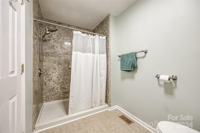 bathroom with tile patterned floors, curtained shower, and toilet